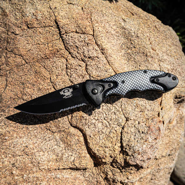 Folding knife with carbon fiber handle on a rock